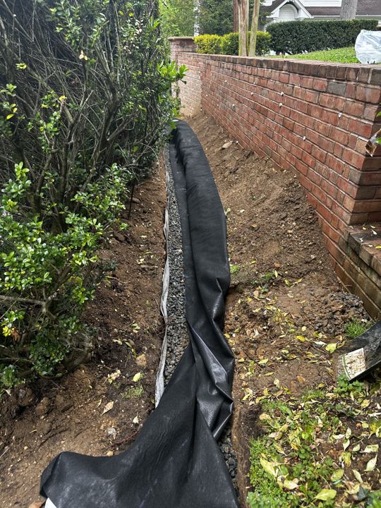 French-drain trench lined with filter fabric along the property line.